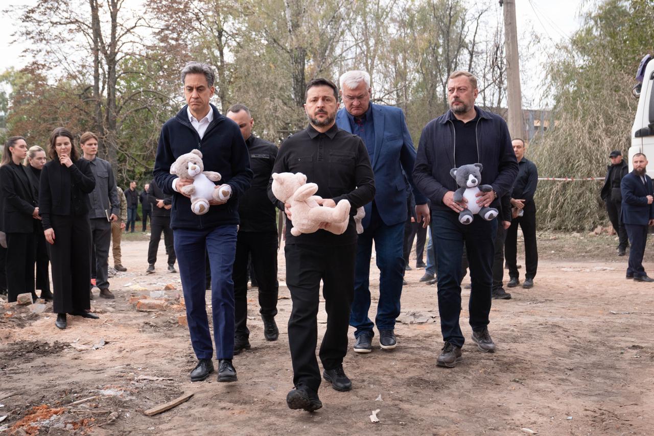 Zelenskyy carries a pink teddy bear through the rubble of Pervomaysk