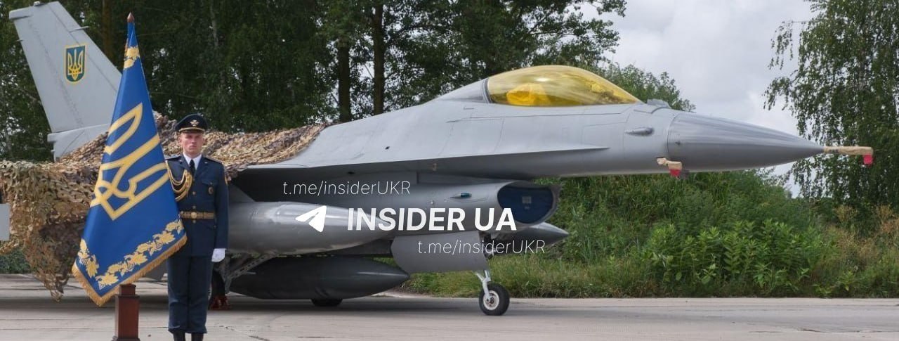 A Ukrainian Air Force officer stands beside a camouflaged F-16